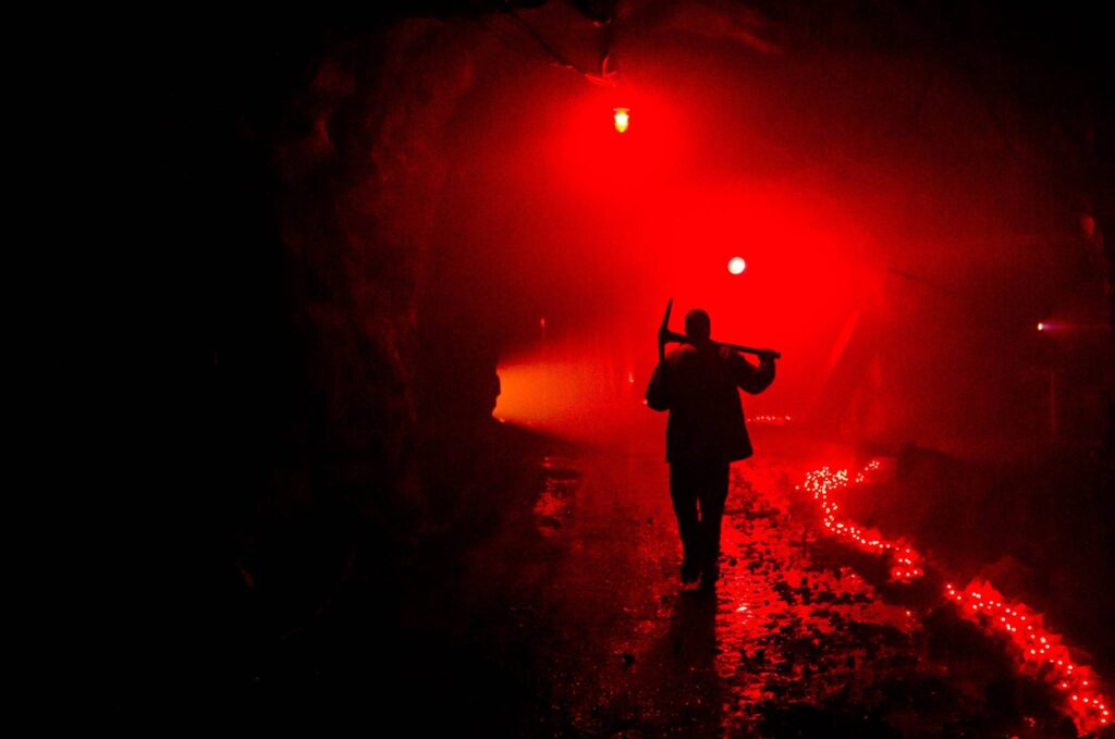 Quincy Mine lit red for the haunted mine event with miner silhouette in center of path.