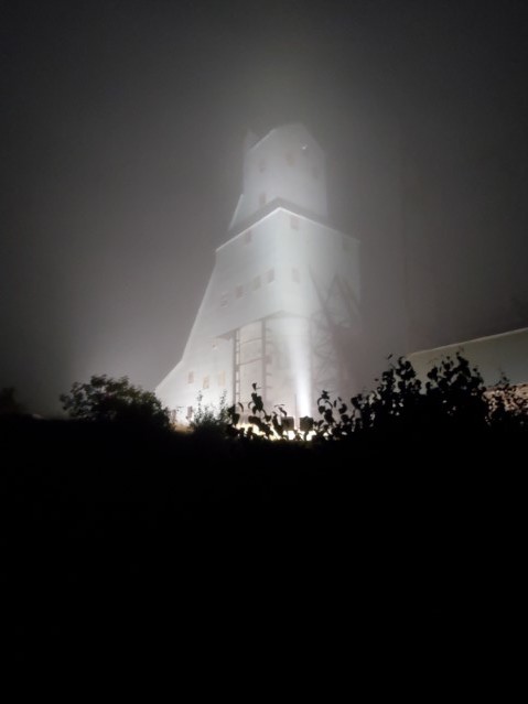 Photo of the shafthouse number 2 lit up at night with some fog.